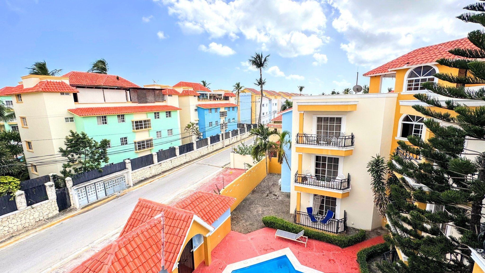 A residential area with colorful buildings, a swimming pool, and a street.