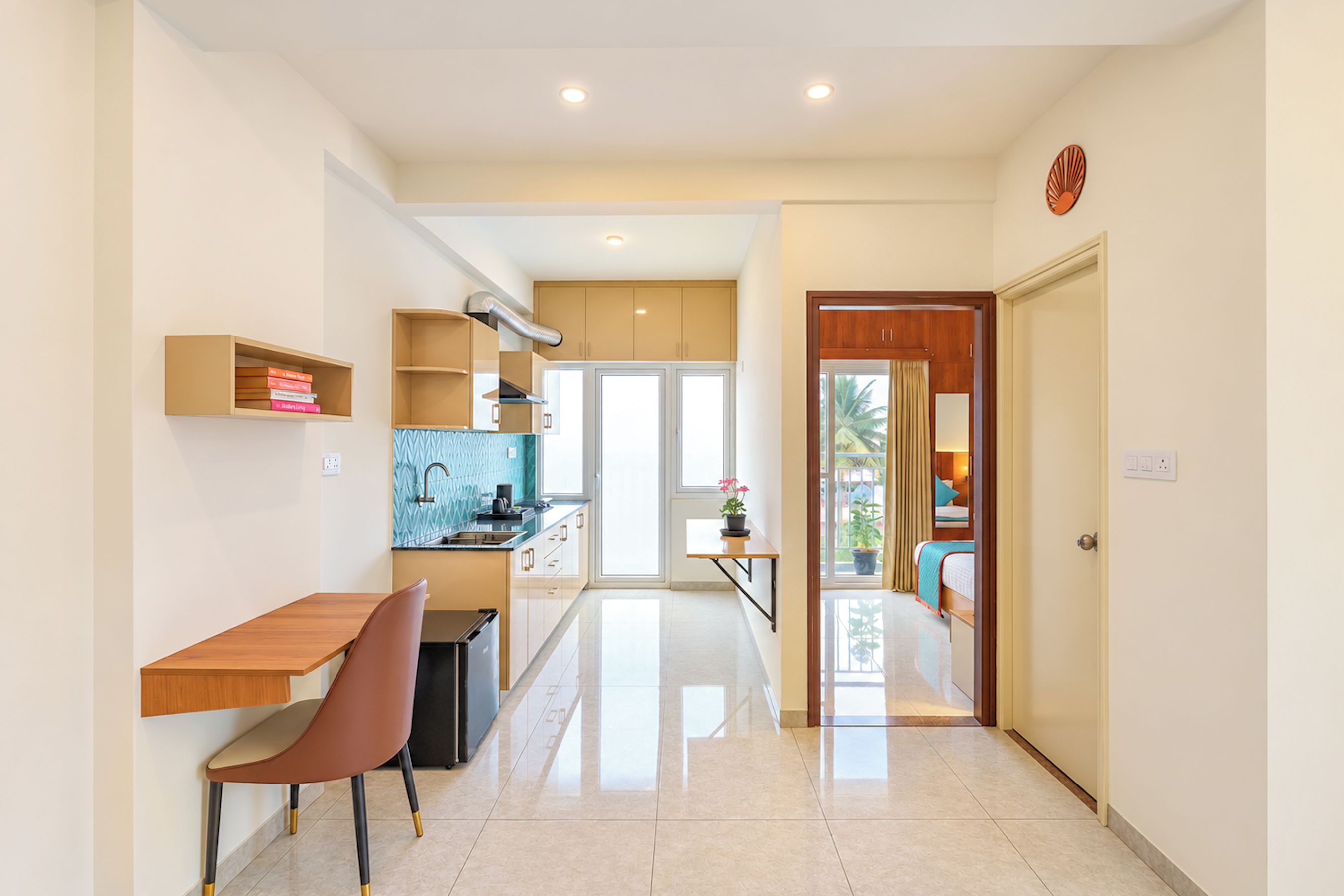 Cozinha moderna com área de refeições, uma mesa pequena e uma cadeira. Há uma janela com vista para palmeiras.