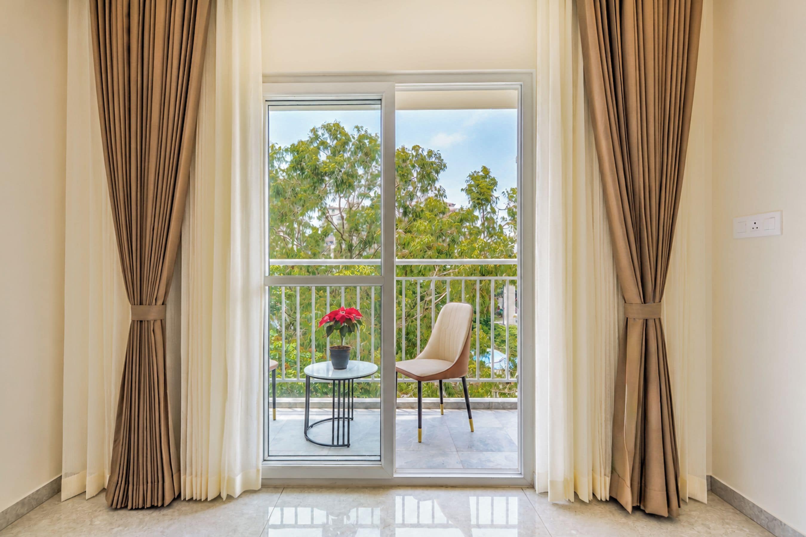 A room with a sliding glass door leading to an outdoor balcony with a chair and a potted plant.