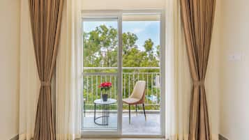 A room with a sliding glass door leading to an outdoor balcony with a chair and a potted plant.