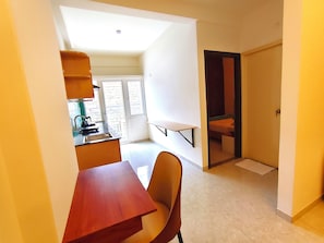 Un espace de vie compact comprenant une kitchenette, un coin repas et une salle de bain.