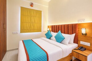 A hotel room with a bed, bedside table, and a wall-mounted telephone.