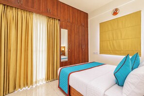 A hotel room with a bed, a wardrobe, a mirror, and a window with curtains. - Terra Rose Suites By Bestinn Leisure (Bengaluru)