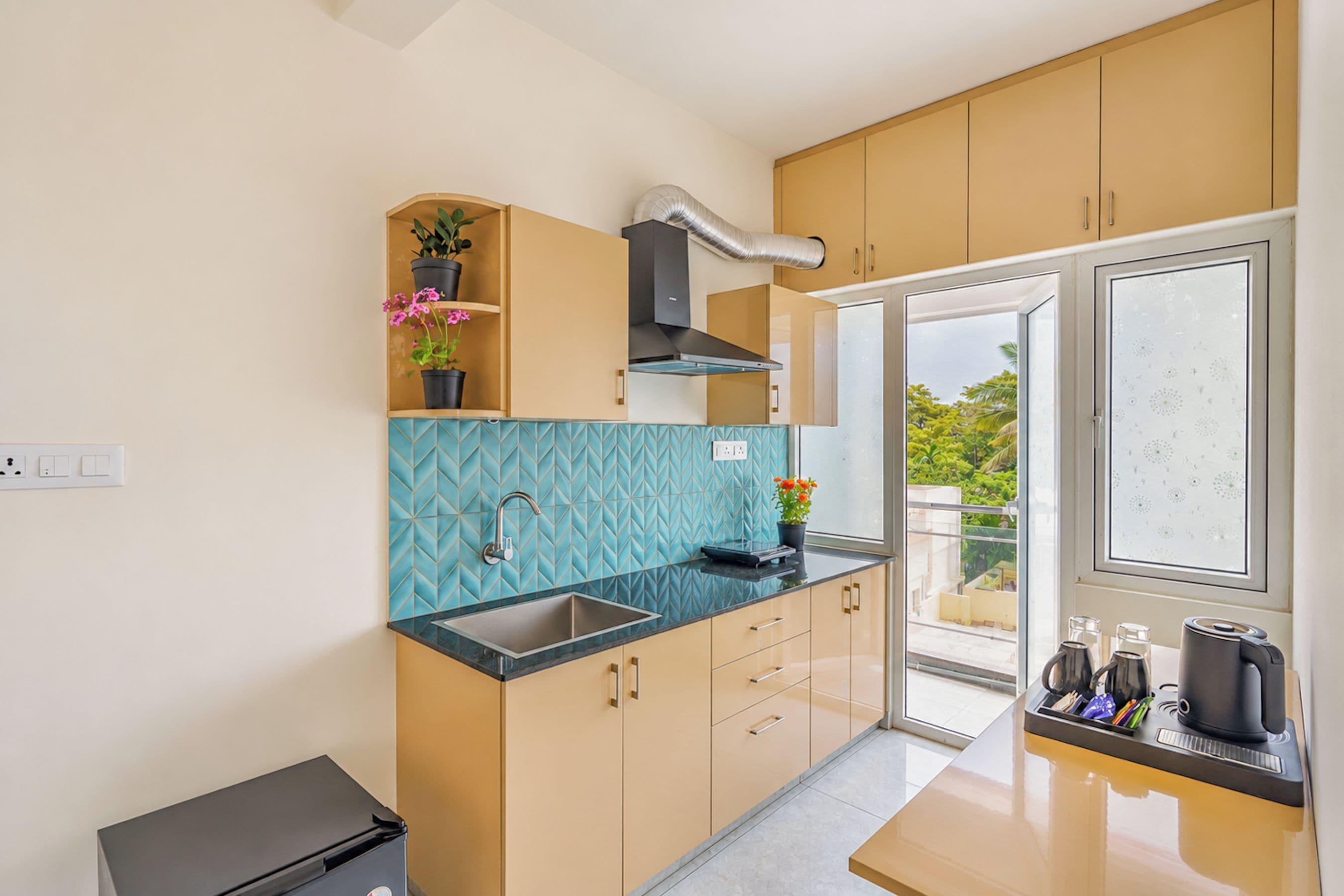 A compact kitchen with a built-in sink, a window with a view, and a small countertop with a kettle.