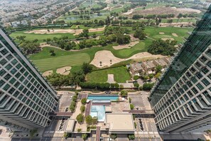 Ein Hochhaus-Hotel mit Blick auf einen Golfplatz, inklusive Schwimmbad und Parkplatz.