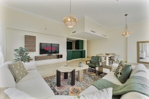 A modern living room with a flat-screen TV, a sofa, a coffee table, and a dining area. - Stunning 2BR Penthouse | 8-Min to Dubai Marina (Dubai)