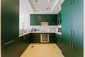 A modern kitchen with green cabinets, a stainless steel oven, and a white countertop. - Stunning 2BR Penthouse | 8-Min to Dubai Marina (Dubai)