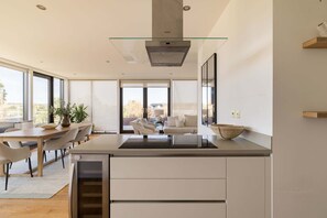 A modern kitchen with a glass cooktop, integrated appliances, and a view to the outdoors. - Terrace Light in the Vale (Greater London)