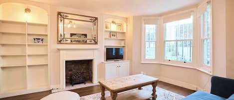 A living room with a fireplace, a television, a coffee table, and a sofa.