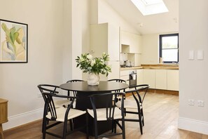 A modern kitchen with white cabinets, a black countertop, and a window. - A Place to Dwell - Tooting (Greater London)