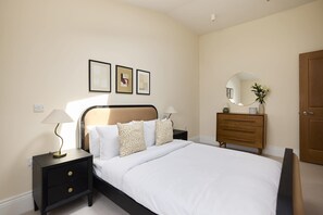 A bedroom with a bed, nightstands, a dresser, a mirror, and wall-mounted artwork. - A Place to Dwell - Tooting (Greater London)