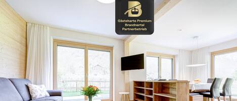 Una sala de estar moderna con un sofá, una mesa de centro, televisor y una estantería de madera.