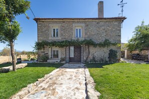 A stone house with a central door, two windows, and a chimney.