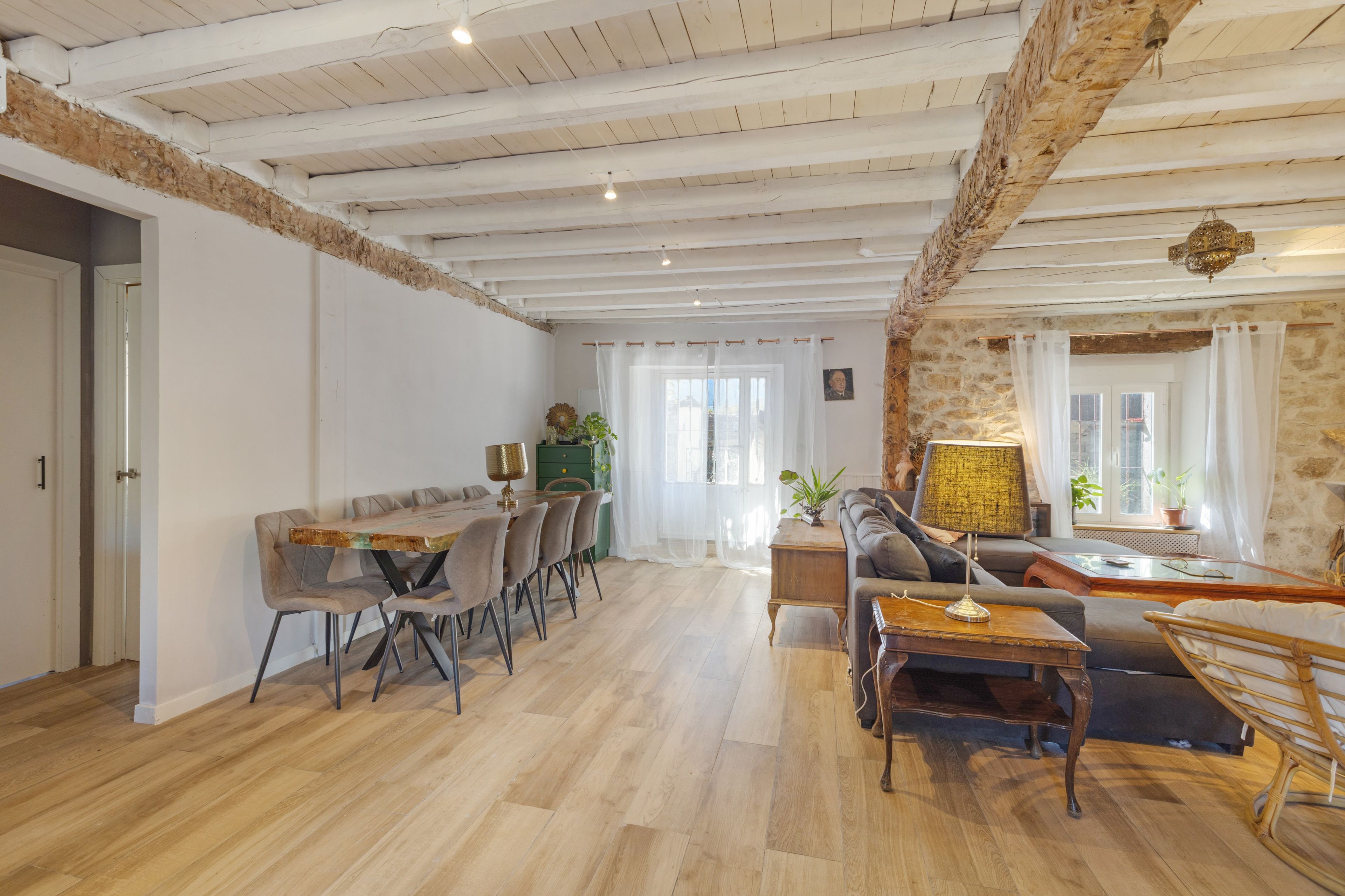Un amplio salón con una mesa de comedor, sofás y una pared de piedra.