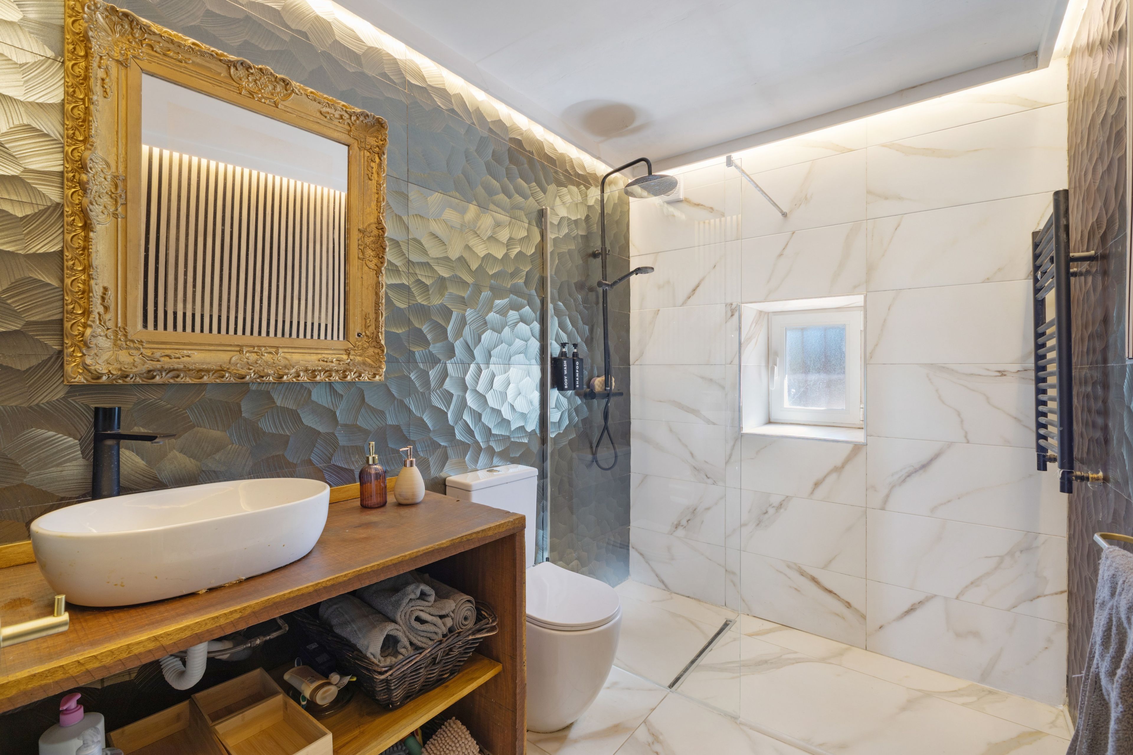 Une salle de bain avec un grand miroir, un lavabo, des toilettes et un espace douche.