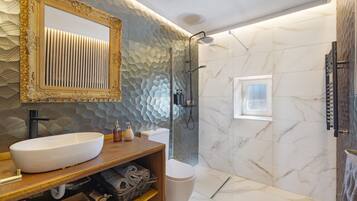 Une salle de bain avec un grand miroir, un lavabo, des toilettes et un espace douche.