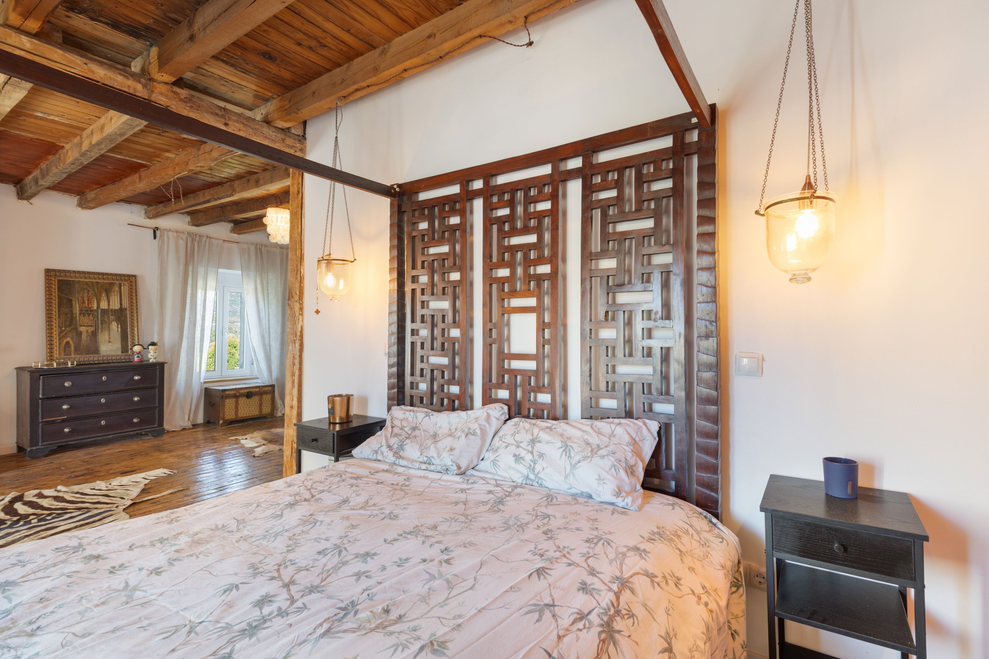Une chambre à coucher avec un grand lit, une tête de lit en bois et deux lampes suspendues.