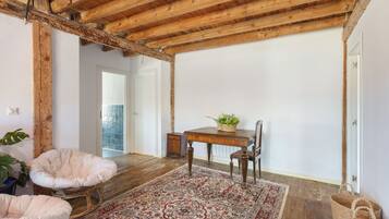 Una habitación con techo de madera, una mesa de comedor con sillas, un tapete estampado y una planta en maceta.