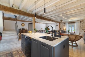 A spacious kitchen with a marble countertop, a built-in dishwasher, and a large island.