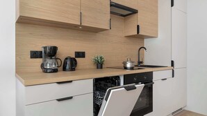 Eine moderne Küche mit Holzschränken, einem integrierten Geschirrspüler und einer Edelstahl-Dunstabzugshaube.