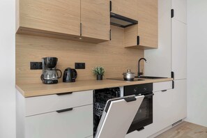 Eine moderne Küche mit Holzschränken, einem integrierten Geschirrspüler und einer Edelstahl-Dunstabzugshaube.