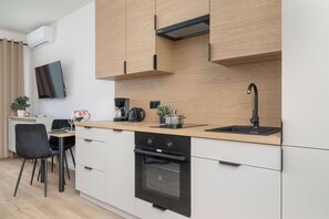Una cocina moderna con horno empotrado, cafetera y pileta.