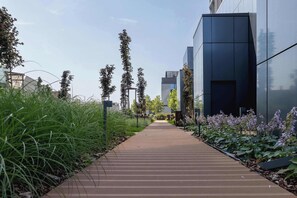 A pathway leading to a modern building with a glass facade. - Modern Studio with a Balcony | Parking | Close to Spodek (Katowice)