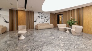 Eine moderne Lobby mit Marmorboden, Sofas, einem Couchtisch und einer Pflanze.