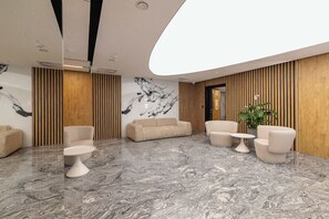 Eine moderne Lobby mit Marmorboden, Sofas, einem Couchtisch und einer Pflanze.