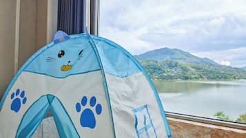 Una carpa con diseño de cara de gato, una ventana que da a vistas de un lago y montañas, y una cortina.