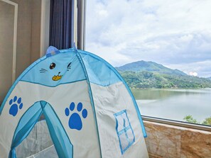 A tent with a cat face design, a window with a view of a lake and mountains, and a curtain. - Baihua Resort Hotel (Guangzhou)