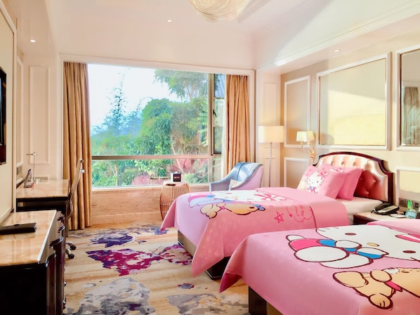 A hotel room with a large window, a bed with pink bedding, a bedside table, a chair, and a desk with a lamp.