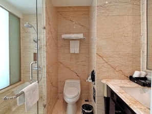 A bathroom with a glass-enclosed shower, a toilet, and a vanity with a sink.