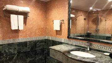 A bathroom with a marble vanity, a large mirror, and a shower area.
