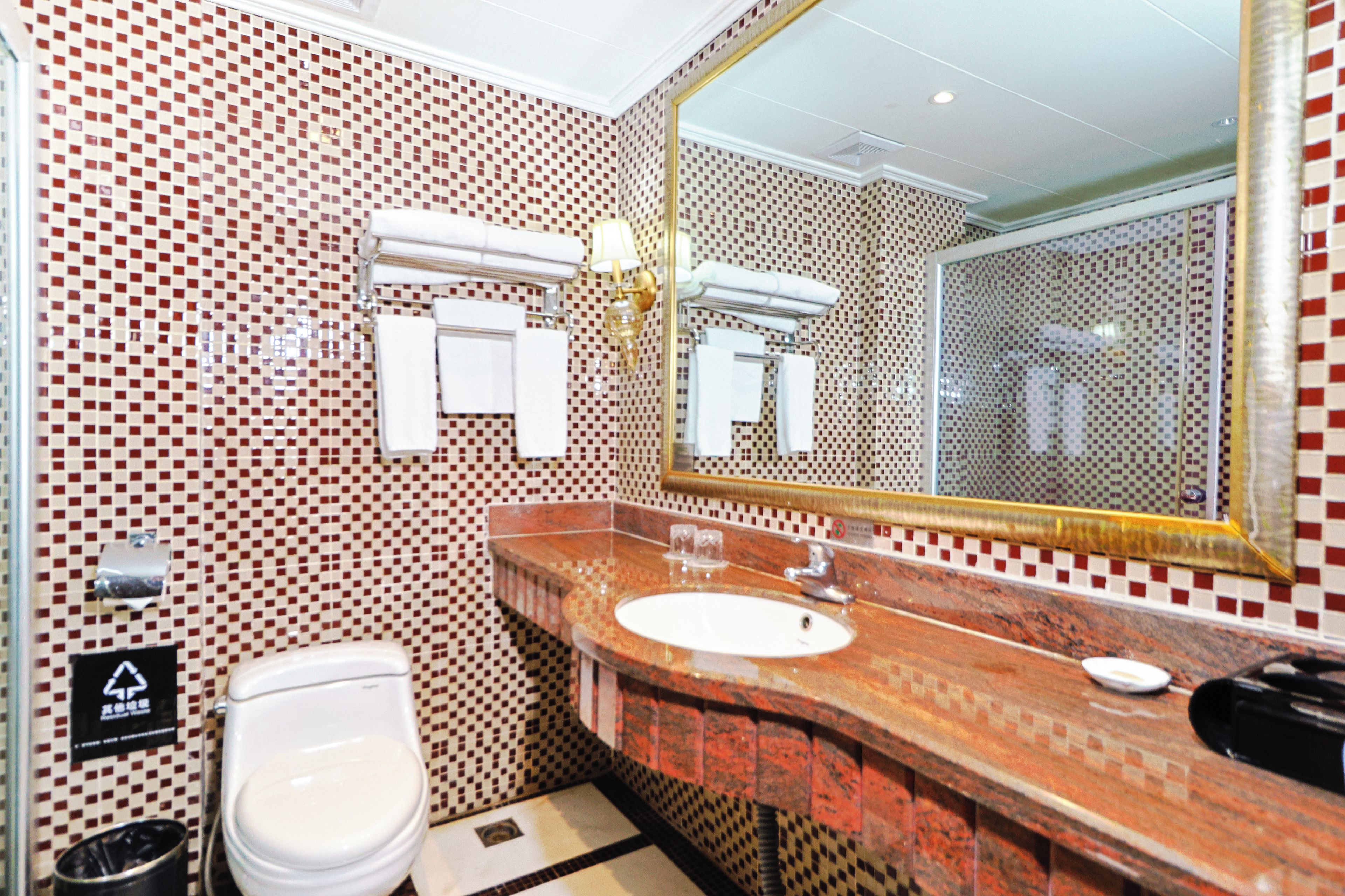A bathroom with a tiled wall, a sink, a mirror, and a toilet.