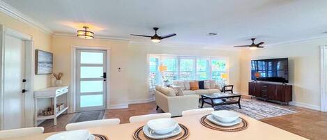 A modern living room with a dining area, a sofa set, and a television.