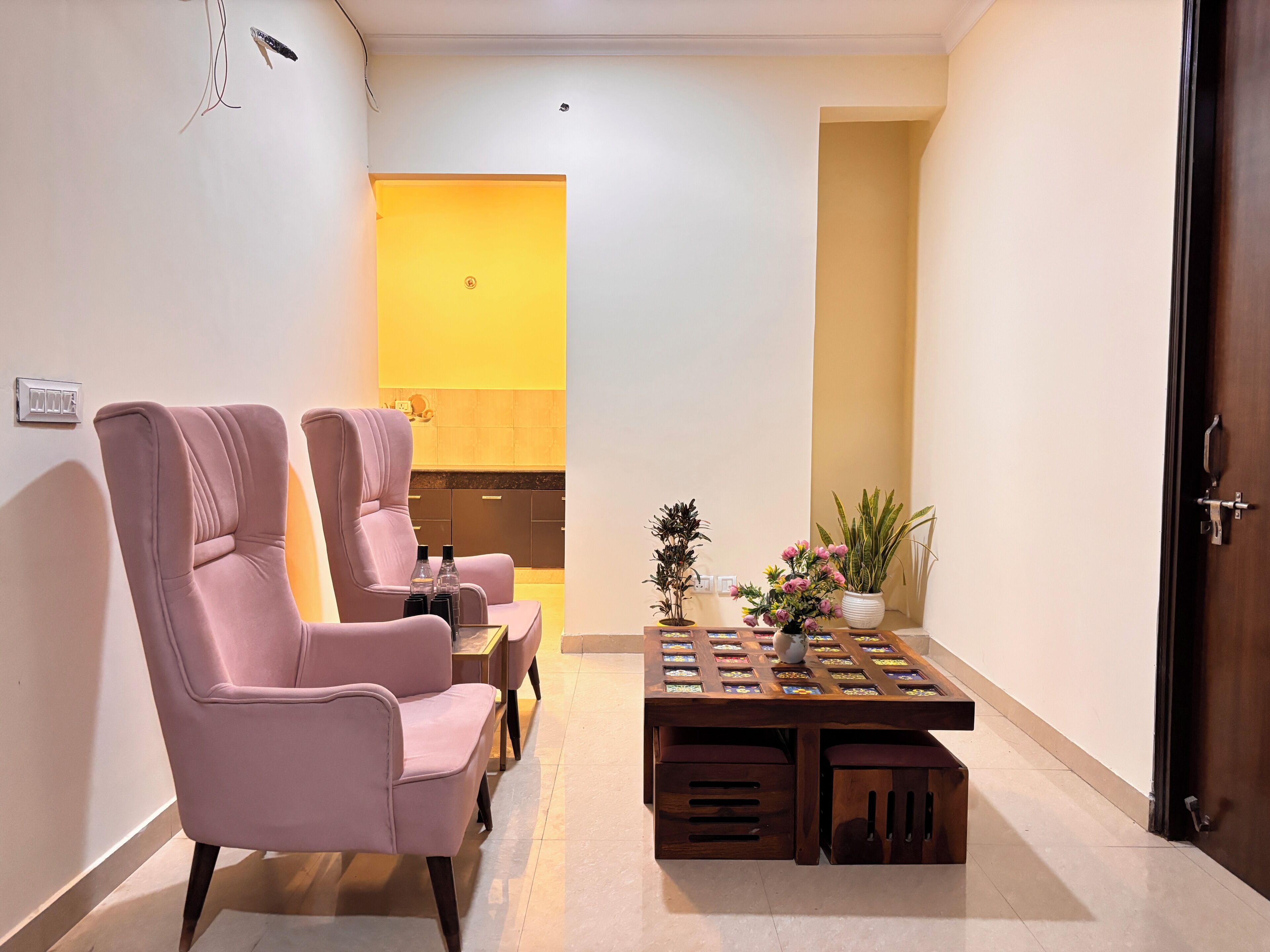 A modern living room with two pink chairs, a wooden coffee table, and a small plant.