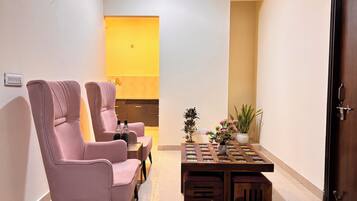 A modern living room with two pink chairs, a wooden coffee table, and a small plant.