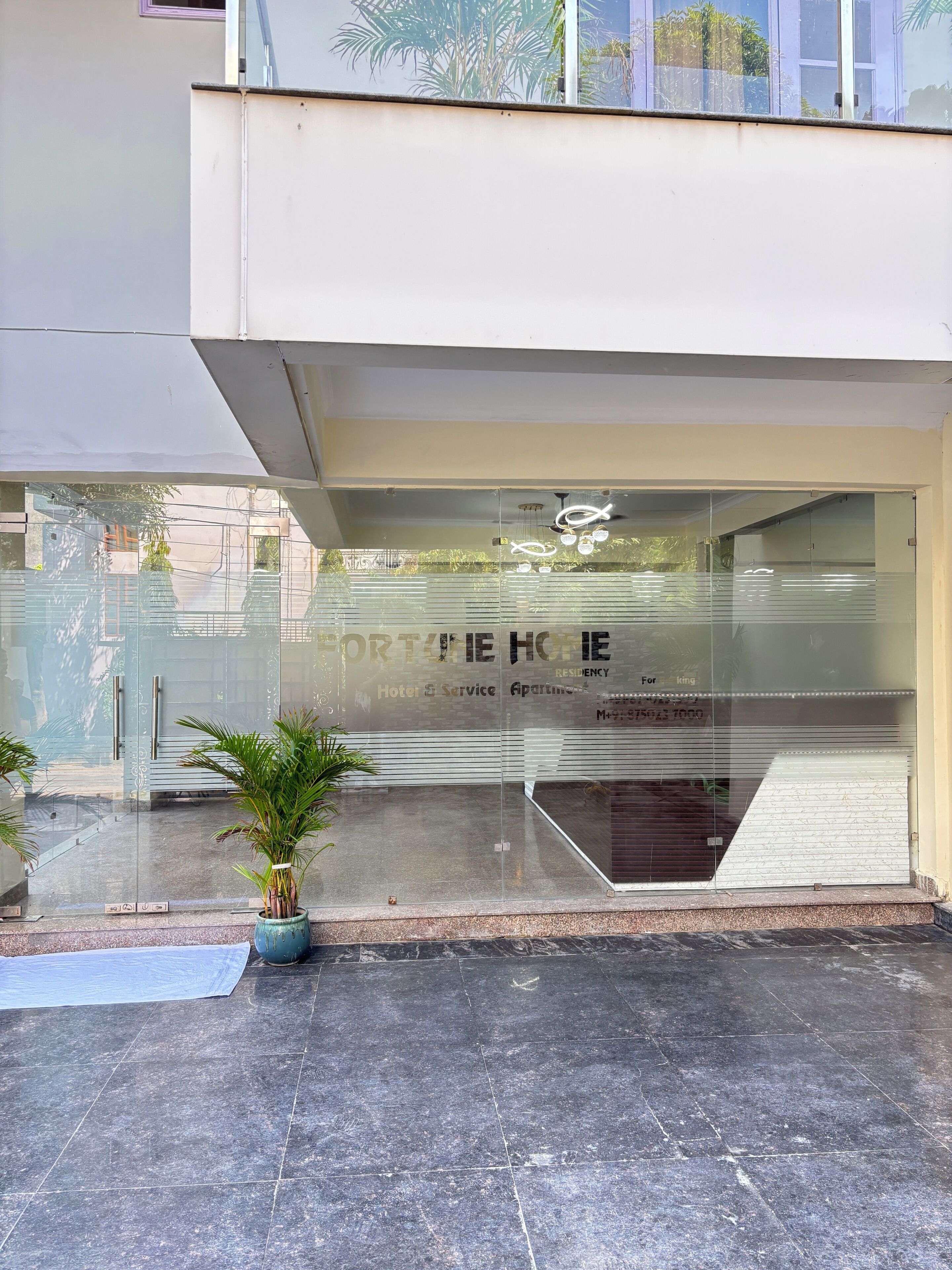 A modern building with a glass facade, a potted plant, and a metal staircase.