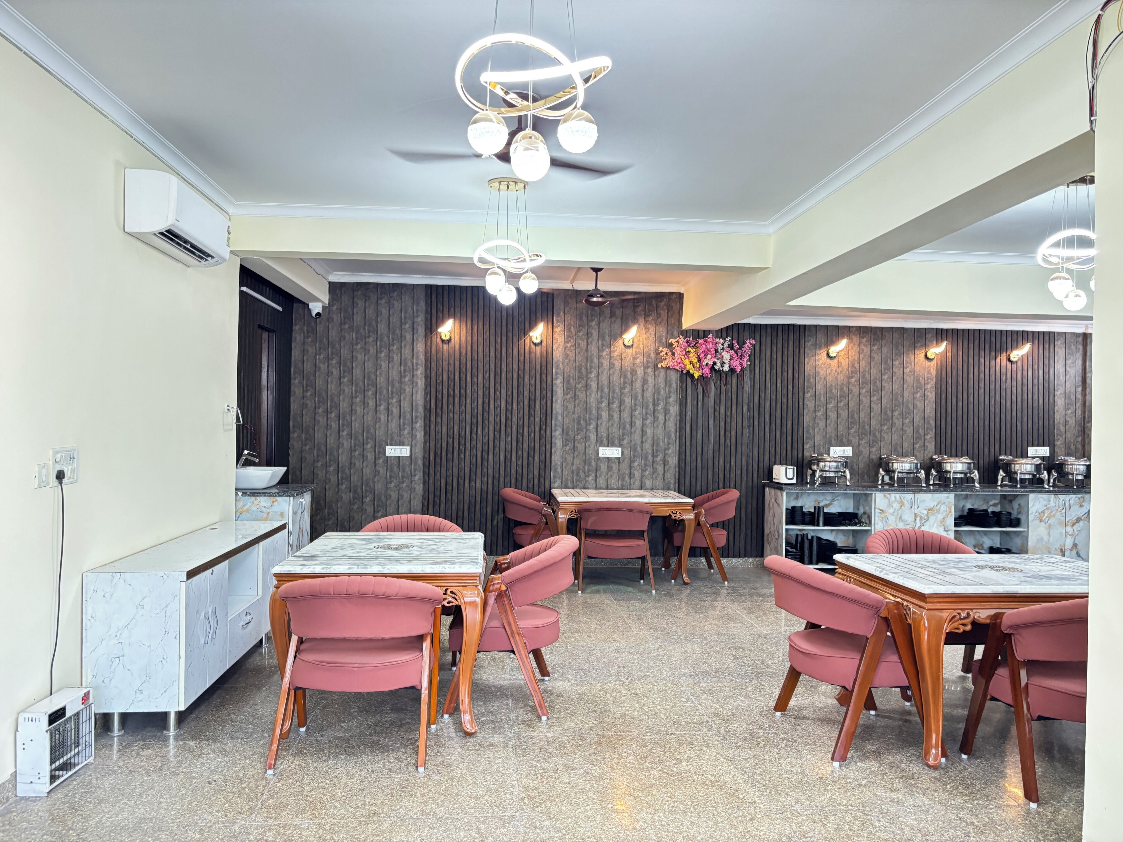 Ein modernes Restaurant mit Marmorarbeitsplatten, roten Sitzmöbeln und einem zentralen Esstisch.