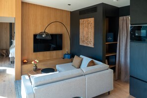 A modern living room with a sofa, a flat-screen TV, a lamp, and a bookshelf. - Infinity 4p in Vama Buz Ului (Vama Buzăului)