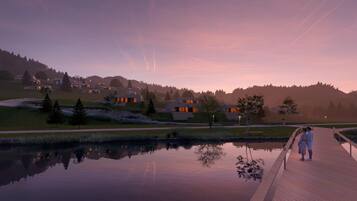 A serene lakeside setting with modern architecture, a wooden boardwalk, and a calm water body reflecting the surroundings.