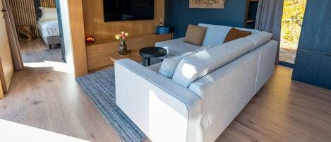 A modern living room with a sofa, a TV mounted on the wall, and a decorative wall piece.