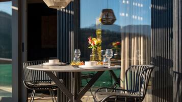 An outdoor dining area with a round table, two chairs, and a vase of flowers.