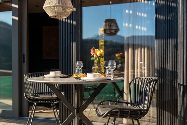 An outdoor dining area with a round table, two chairs, and a vase of flowers.
