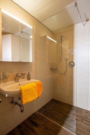 Ein modernes Badezimmer mit Waschbecken, Spiegel und Dusche.