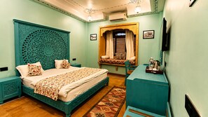 A bedroom with a bed, nightstands, a dresser, a window with curtains, and a wall-mounted air conditioner.