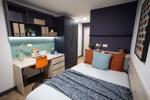 Ein gemütliches Schlafzimmer mit Schreibtisch, Bett und Stauraumschränken.