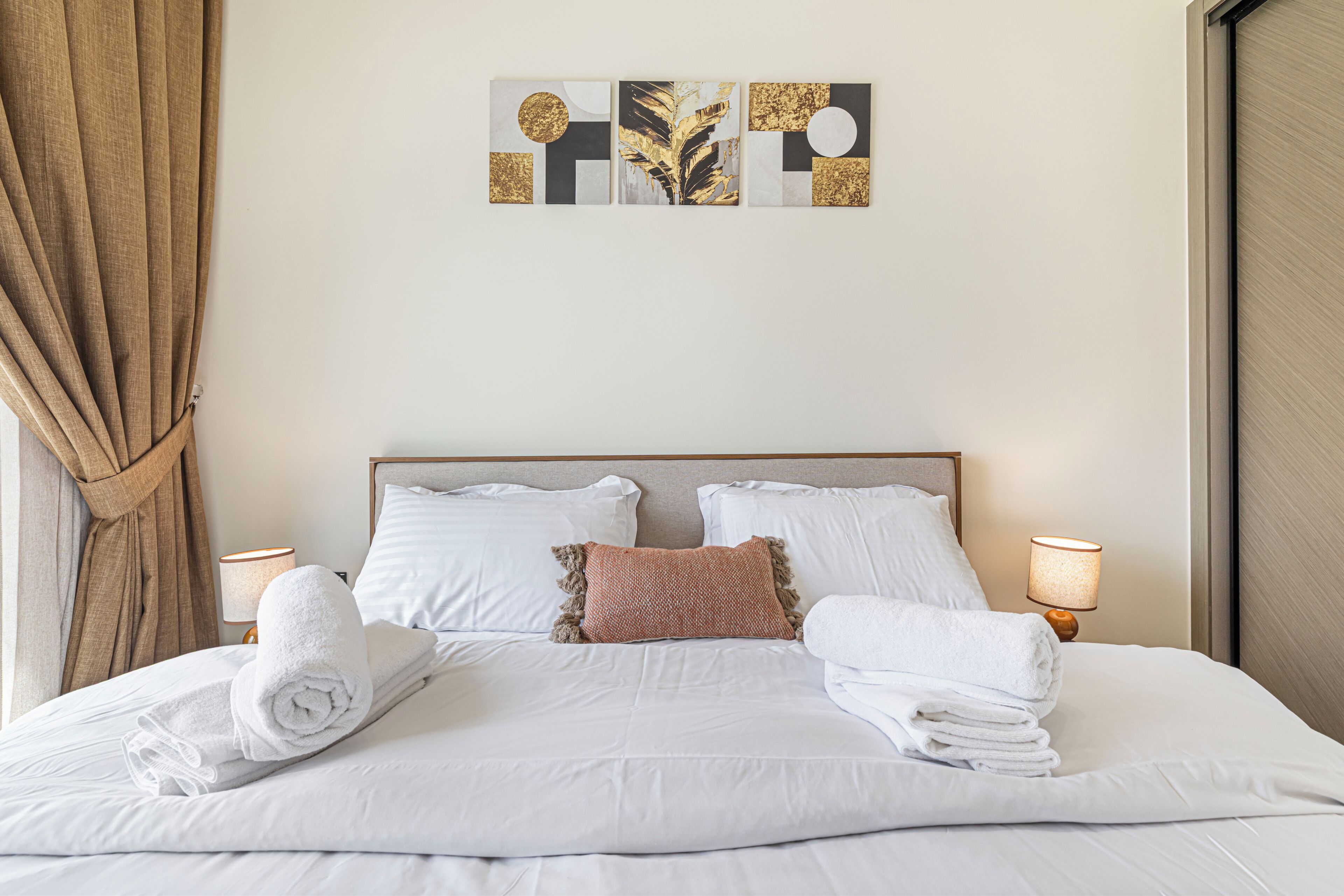 Un lit bien fait, avec du linge de lit blanc, une tête de lit et deux lampes de chevet.