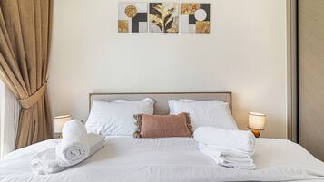 A neatly made bed with white linens, a headboard, and two bedside lamps.